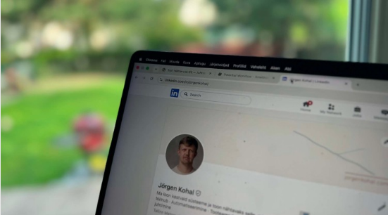 Sülearvuti ekraanil Jörgen Kohali LinkedIn-profiil, taustal roheline aed.